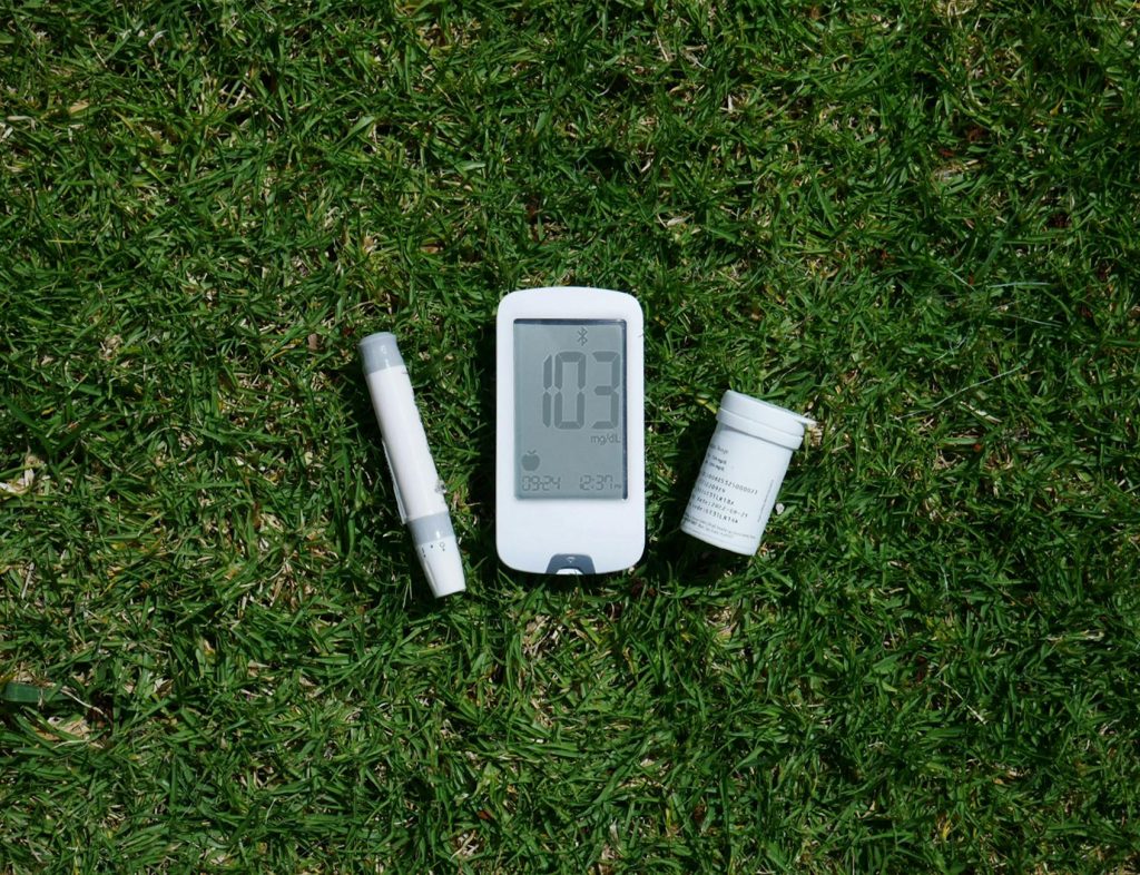 a blood glucose meter and a pill on the grass